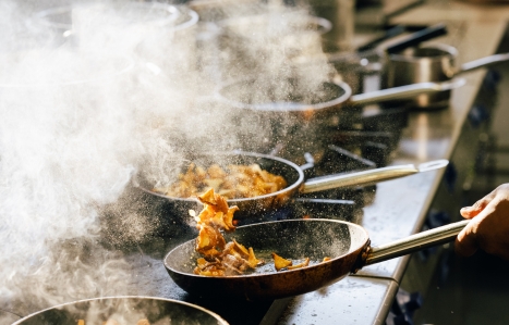 two frying pans letting off steam on a cooking hob