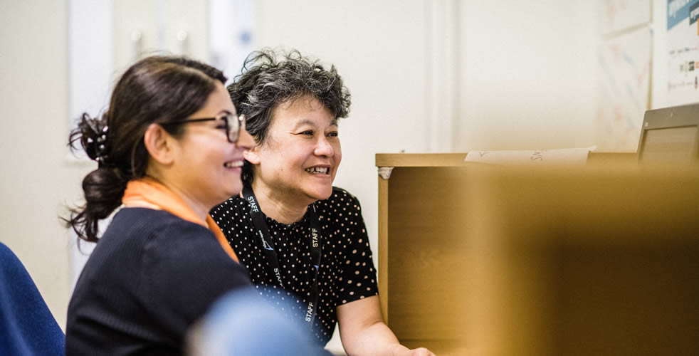 Two adult students working together on a computer