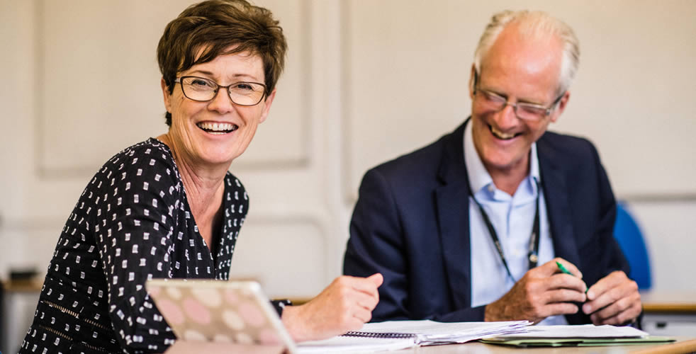 Two adult students laughing together at a table