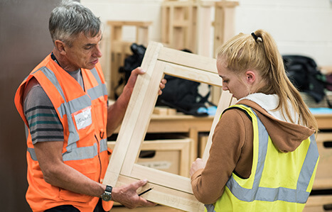 Teacher and student holding wooden frame