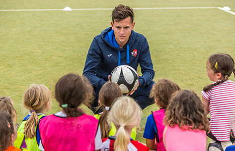 Male Apprenticeship student coaching children sport