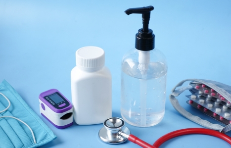 Surgical masks, thermometer and hand sanitizer on blue background