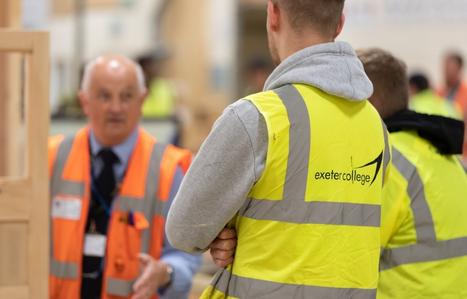 Exeter College construction students in yellow high vis jackets listening to a member of staff in an orange high vis jacket