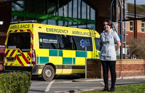 student stood in front of hospital with an ambulance behind them