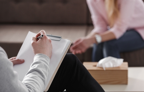 Close-up of therapist hand writing notes during a counselling session