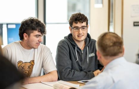 Students speaking to teacher at their desk
