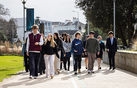 Large group of students walking onto Hele site chatting with each other