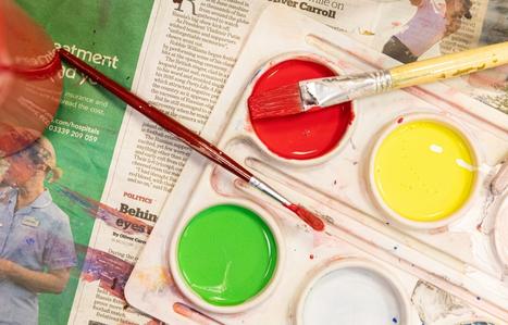 Paint palette filled with red green and yellow on old newspapers