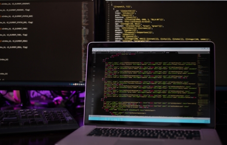 Three computer screens with computer programming code