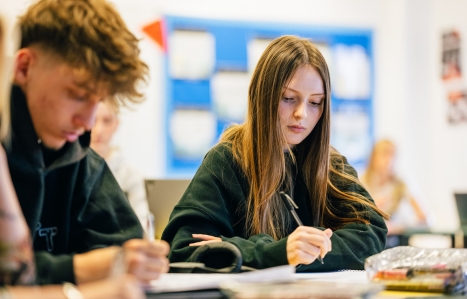 Students sat at desk writing in their books