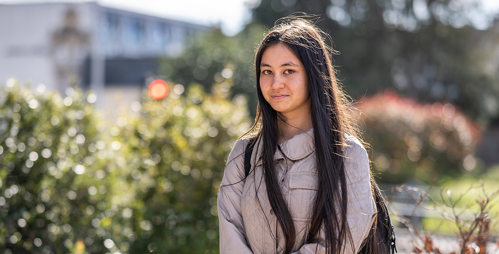 Female Student portrait smiling at the camera wearing a grey coat