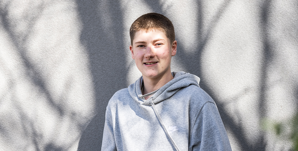 Male Student portrait smiling at the camera wearing a grey Nike hoodie