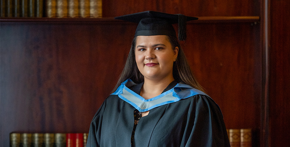 graduating student smiling at camera in their gown