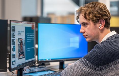 male student looking at two computer screens
