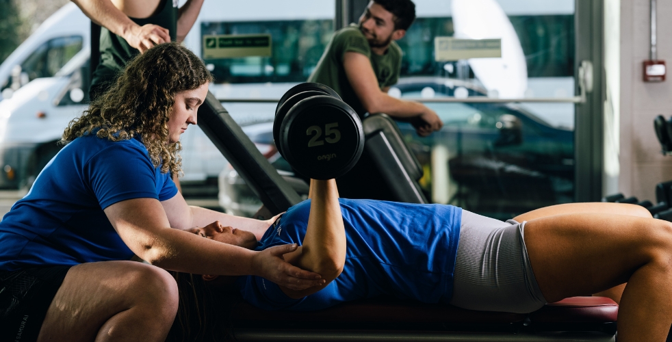 Two female students using weights in the gym