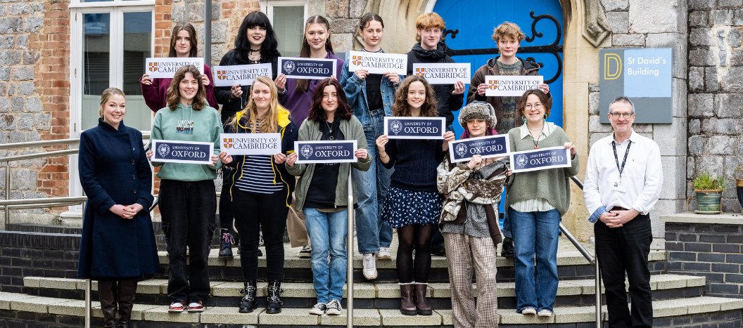 Future Oxbridge students stood on steps outside St David's building holding signs of the university that they have been offered places