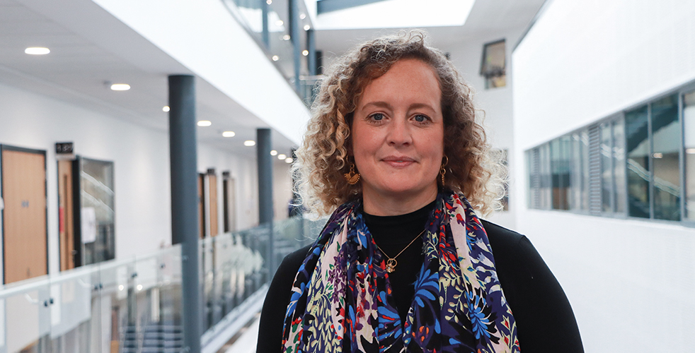 Women stood smiling at the camera with a colourful scarf and blond curly hair
