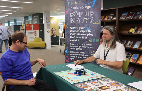 Exeter College Pop Up maths stand with two people playing monopoly