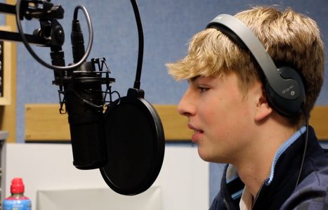 Student speaking into radio mic with headphones on