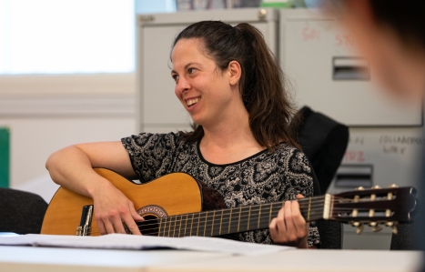 Adult student playing guitar smiling