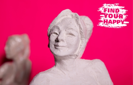 Sculpture with a bright pink background and the find your happy logo