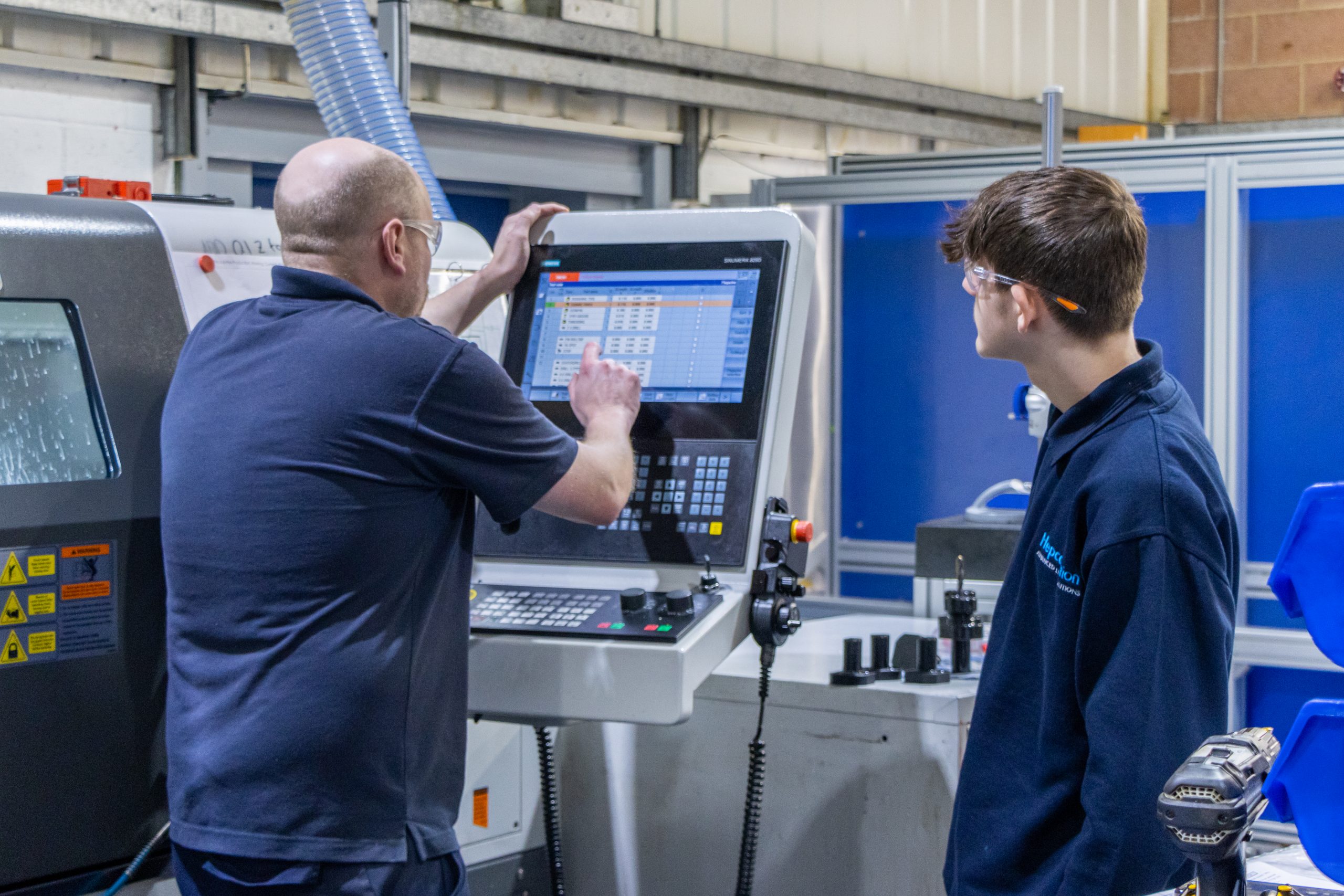 student watching an employee operate machinery