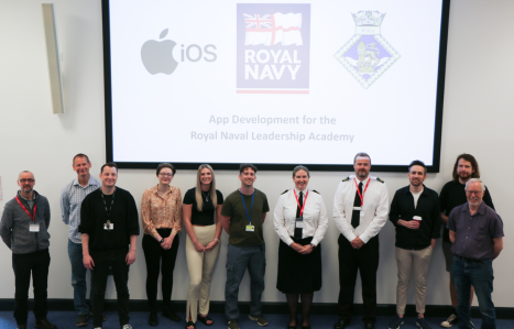 Group of staff and royal navy staff stood smiling at the camera