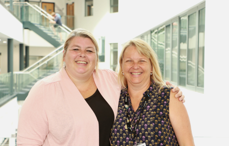 Donna stands with her teacher and smiles at the camera