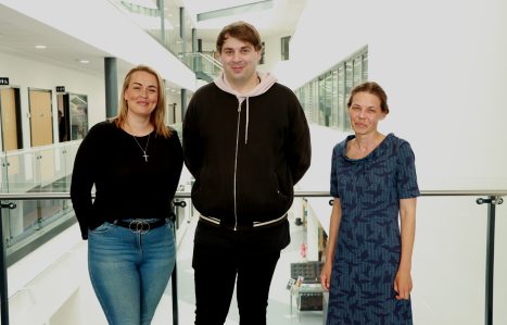 Three adult learners stand in the IoT and smile at the camera