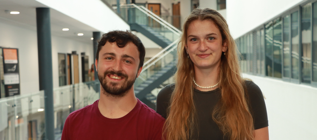 Two adult learners stand in the IoT and smile at the camera