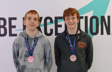 Two students with awards around their necks smiling at the camera