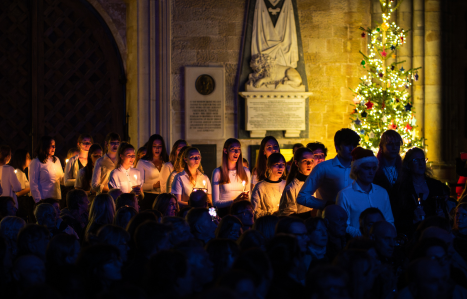 Group of students singing at the front of the cathedral in candle light