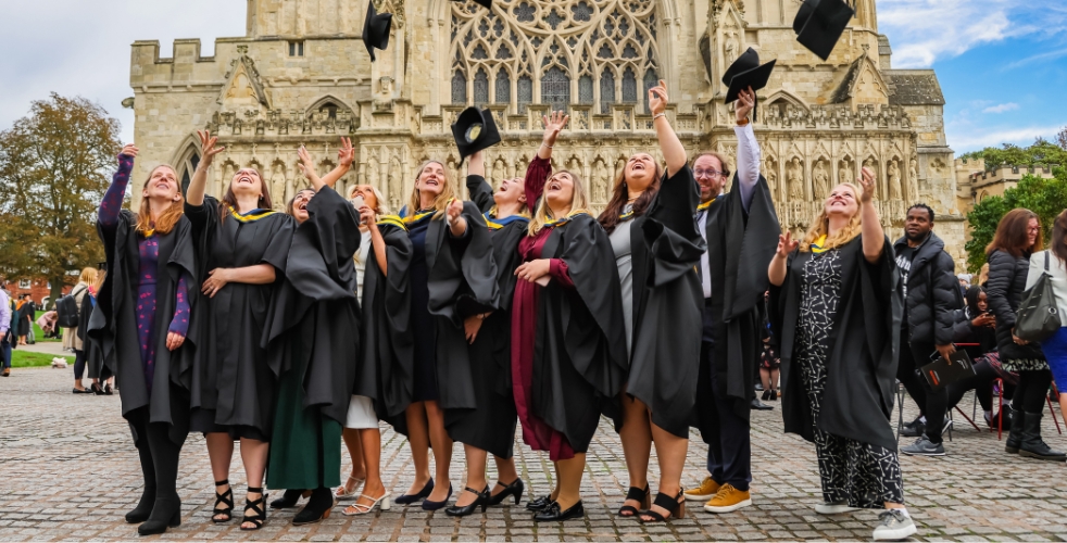 Graduates outside cathedral throwing hats