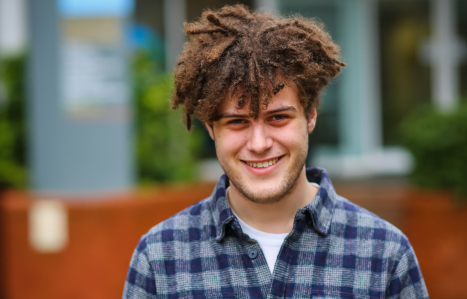 A boy in a checked shirt smiles at the camera