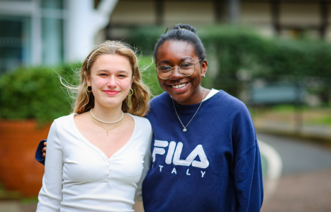 Two girls hug and smile at the camera.