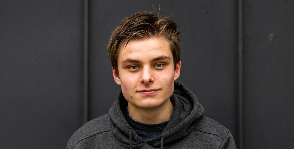 Profile of Daniel against a dark grey background looking at the camera