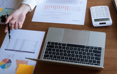 accountant working on financial report on desk using calculator, laptop