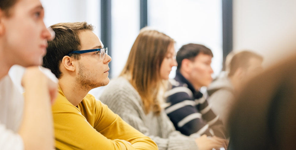 focus on one adult learner looking up in class in a line of adult learners