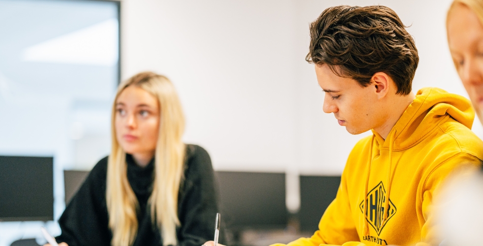 two adult learners in class, one looking down and one looking up
