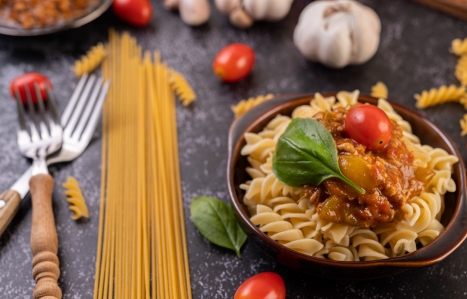 Macaroni sauteed with tomatoes and basil on a gray plate.