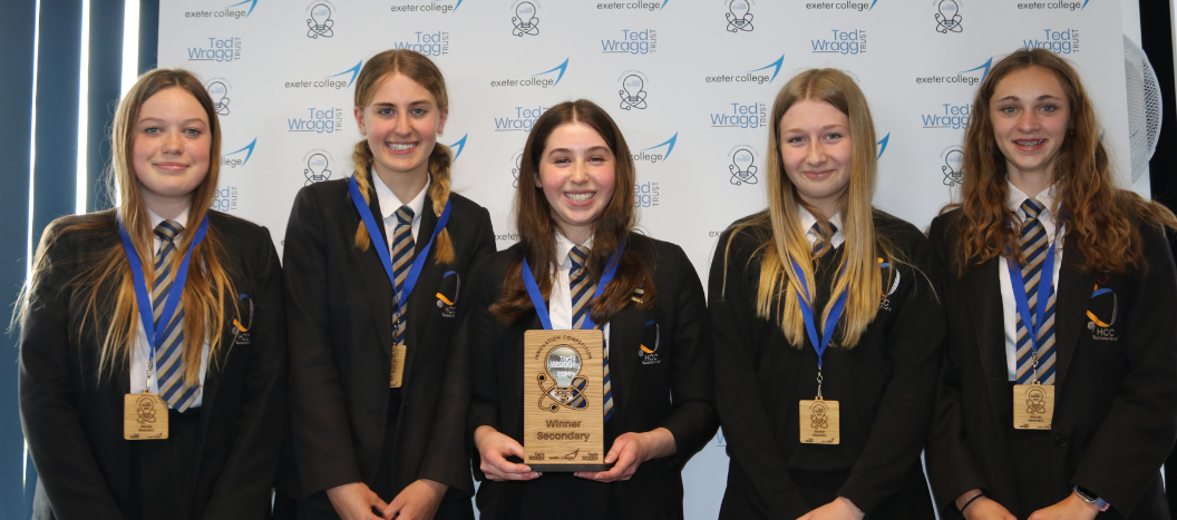 Group of girls stood side by side smiling at the camera holding their award for the Innovation Competition.