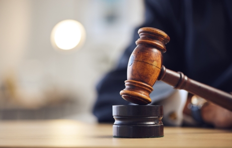 Close up of a gavel on a wooden desk background.