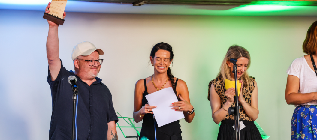 An adult learner collects his award from on stage.