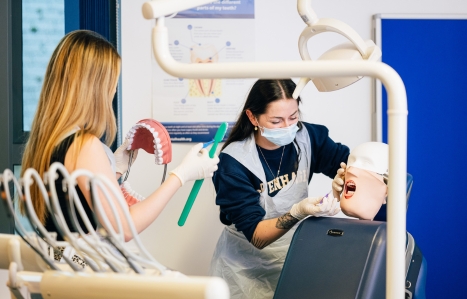 Two dental nursing students working in the dental suite on a dummy model