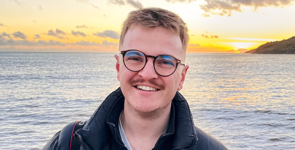 Profile photo of Sam with the ocean behind him