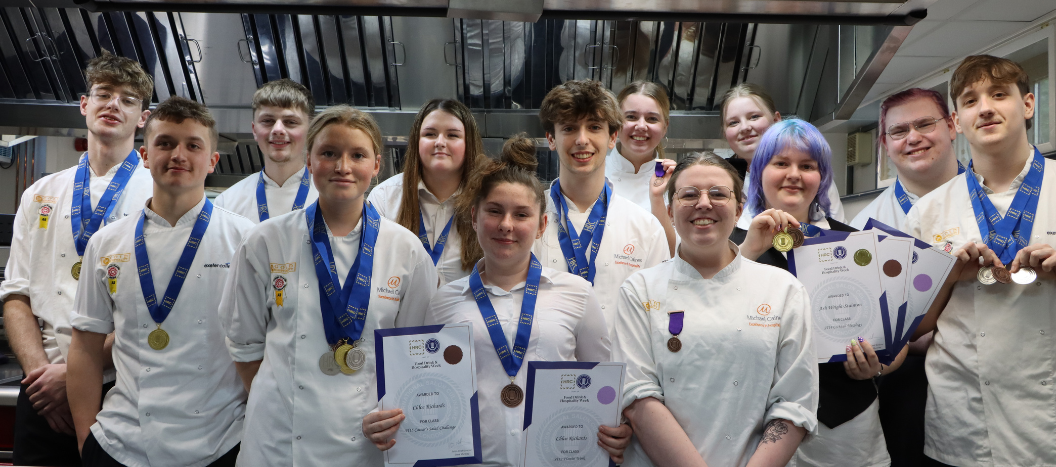 Students in their chef whites post in a kitchen with their competition medals