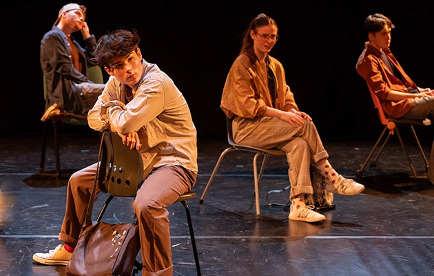 Performing Arts students sat on chairs mid performance