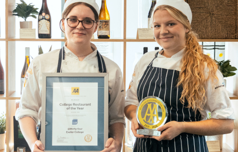 Two female student chefs hold up a trophy and certificate