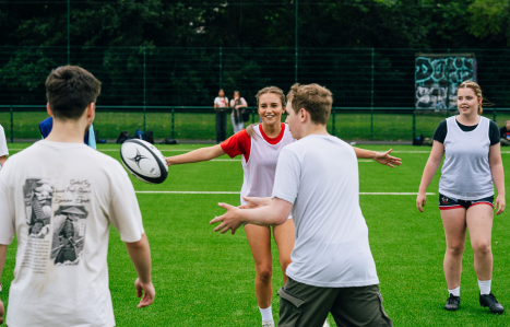 A group of young people on a pitch with a rugby ball