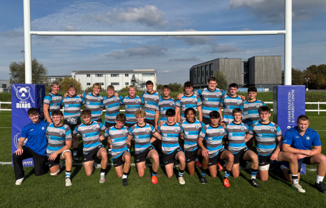 A male rugby team pose in their kit.